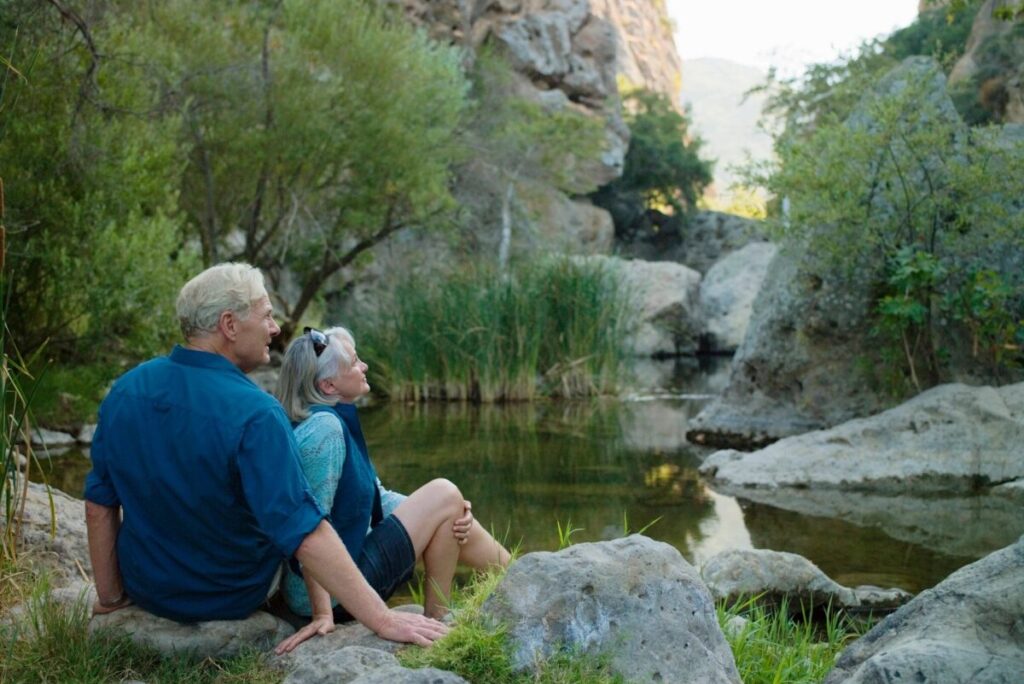 Two people sitting on the shore of a river